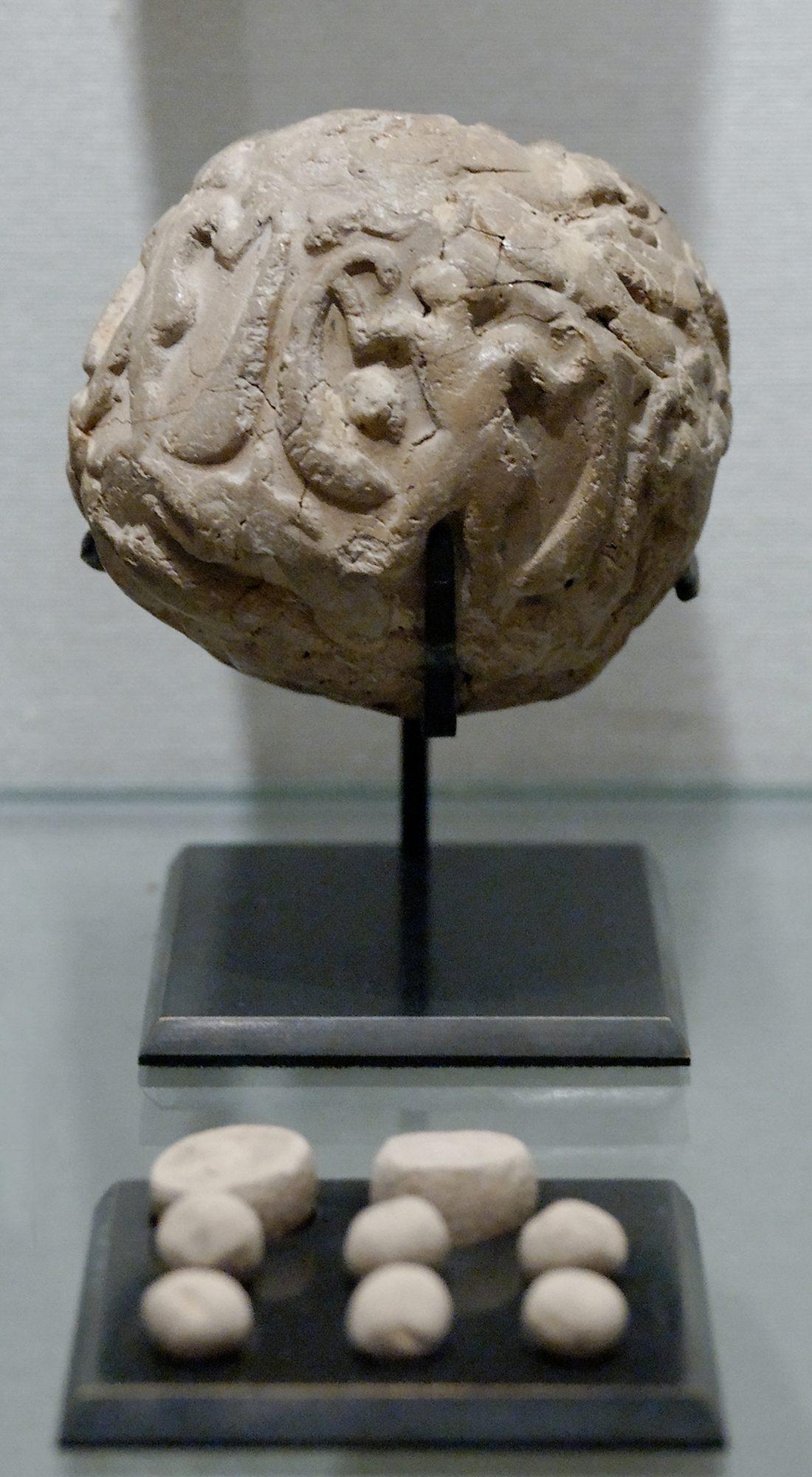 Clay accounting envelope, a bulla, displayed with the small clay tokens it once sealed